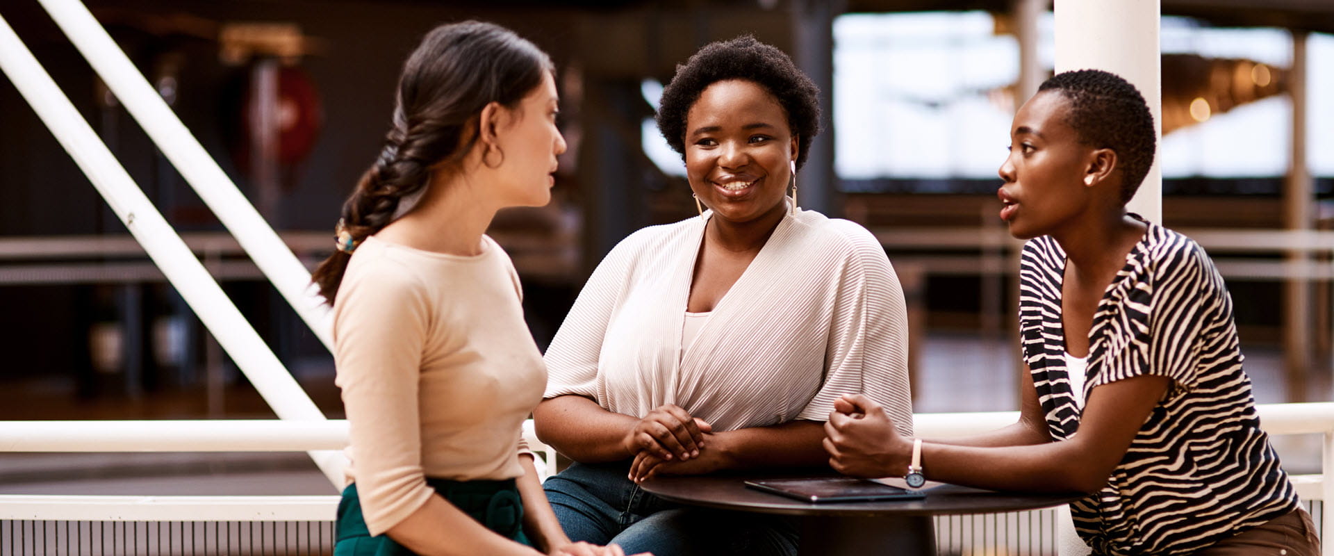 Three diverse individuals engaged in a friendly conversation at a modern office or coworking space. Three diverse individuals engaged in a friendly conversation at a modern office or coworking space.