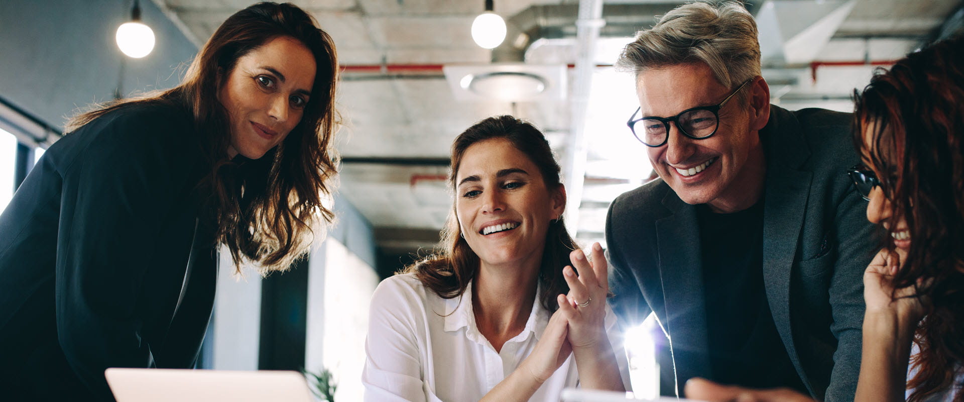 group of smiling professional people looking at laptop