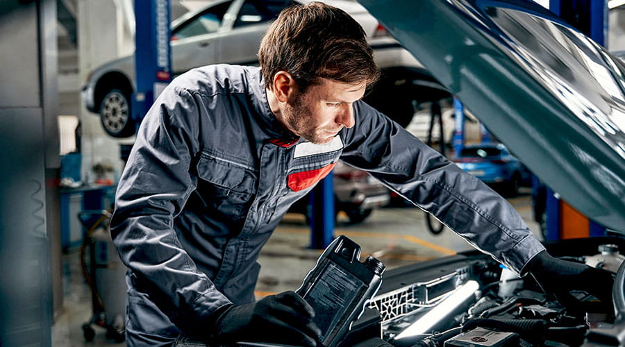  Mechanic working under car hood in automotive workshop