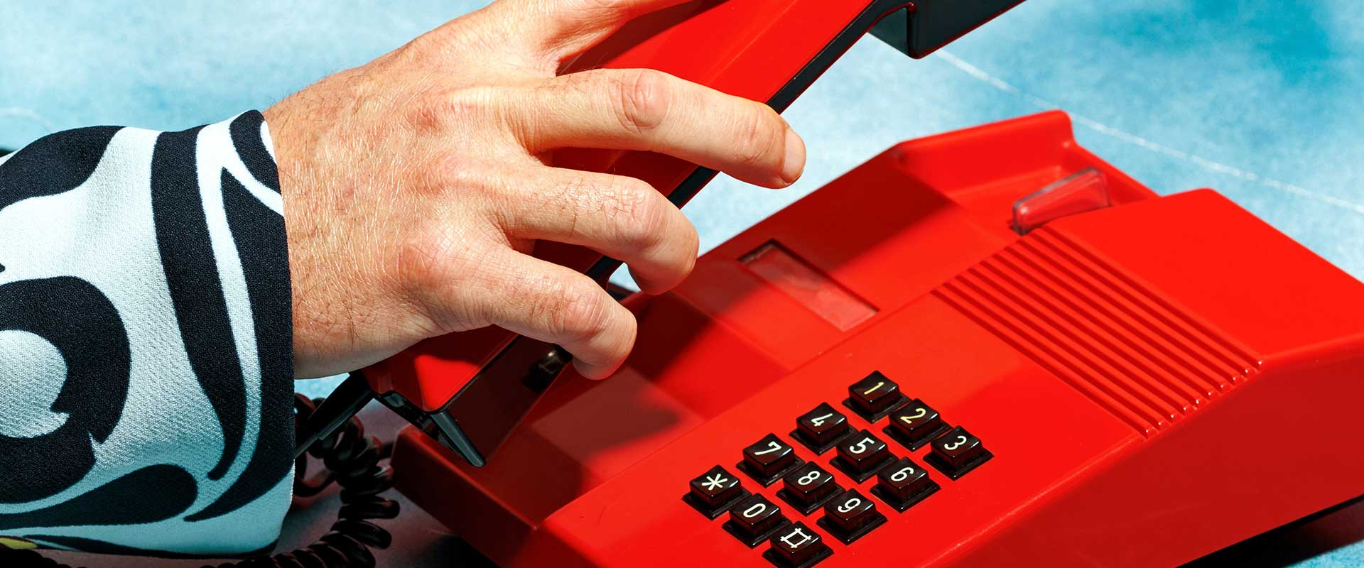 Primo piano di mani che usano la tastiera rossa di un telefono. Primo piano di mani che usano la tastiera rossa di un telefono.