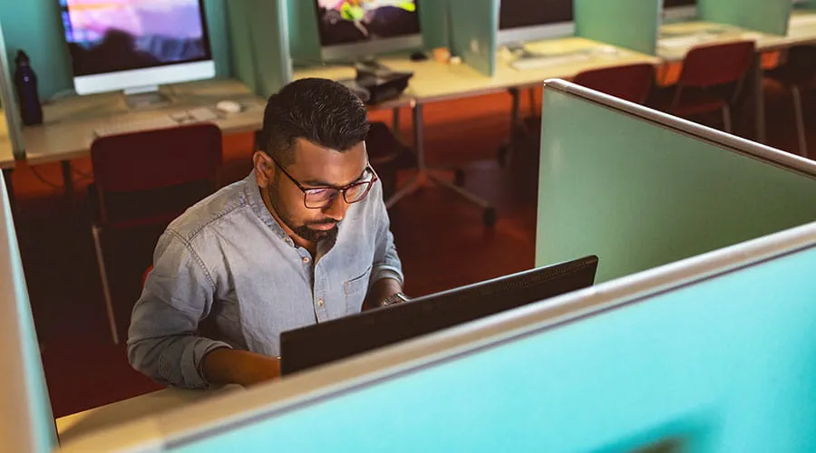 Persona che lavora al computer in un cubicolo d'ufficio Persona che lavora al computer in un cubicolo d'ufficio