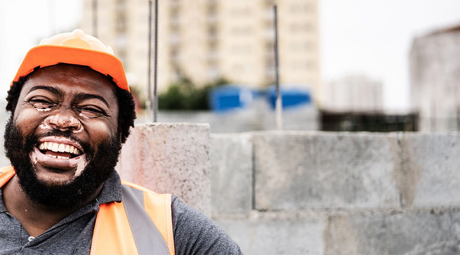 Operaio con dispositivi di sicurezza sorridente in un ambiente esterno